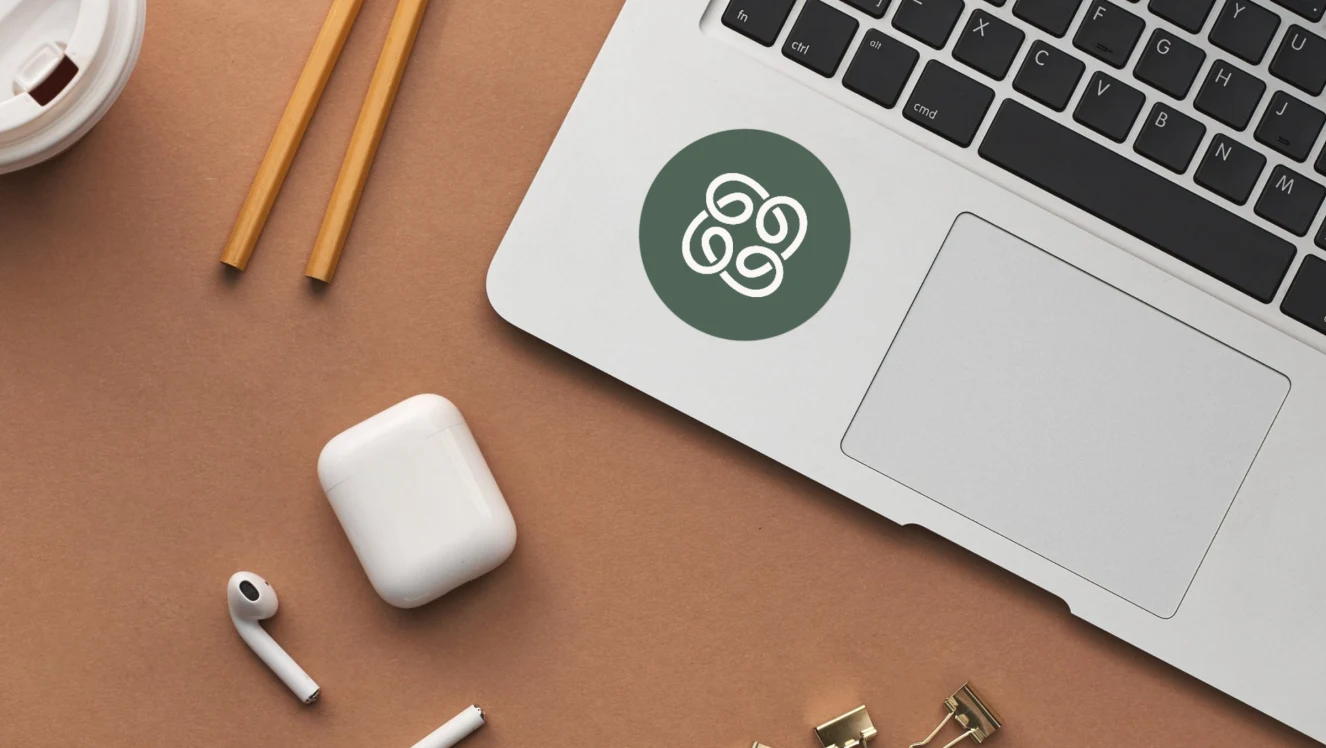 Greensync Studio’s green mark on a laptop beside pencils and earbuds on a warm desk